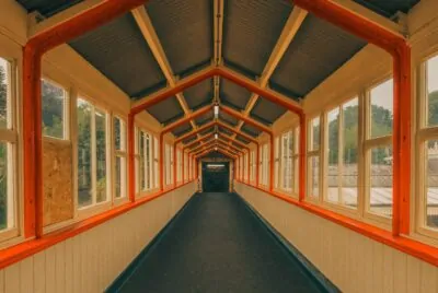 Wes Anderson aesthetic interior — symmetrical hallway with orange trim, vintage windows, and pastel walls