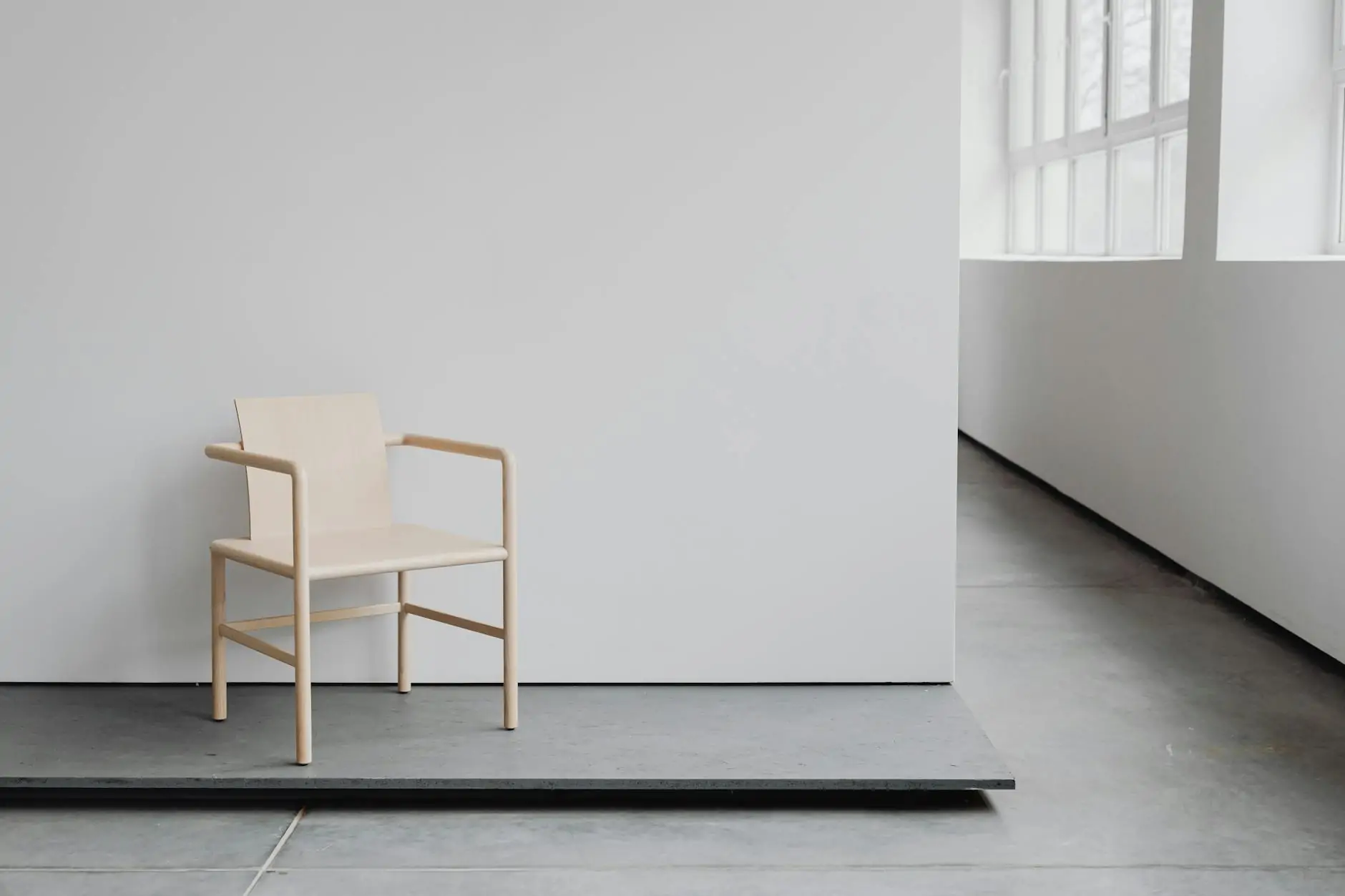 Minimalist wooden Japandi chair against a plaster wall