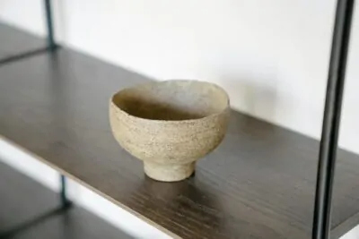 Wabi sabi interior with raw plaster wall, handmade ceramic and aged wood table