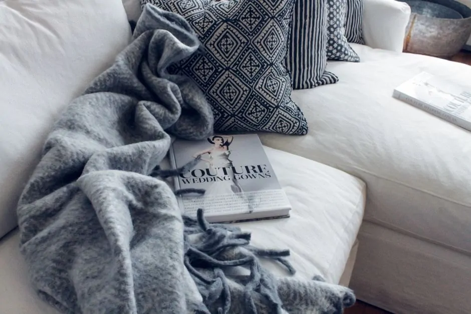 Gray throw blanket draped across a white sofa with patterned pillows
