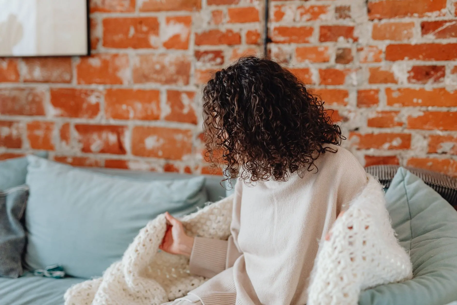 Adult wrapped in an oversized blanket while sitting on a sofa