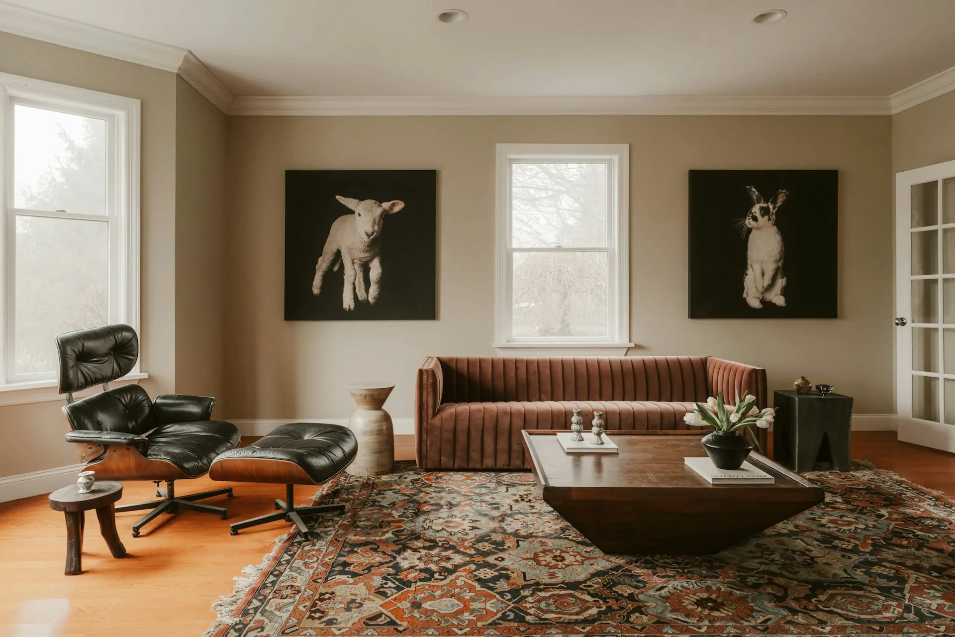 Black Eames-style lounge chair with molded wood shell and leather cushions in a living room