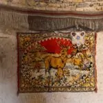 A vintage woven rug displayed vertically on a rustic interior wall