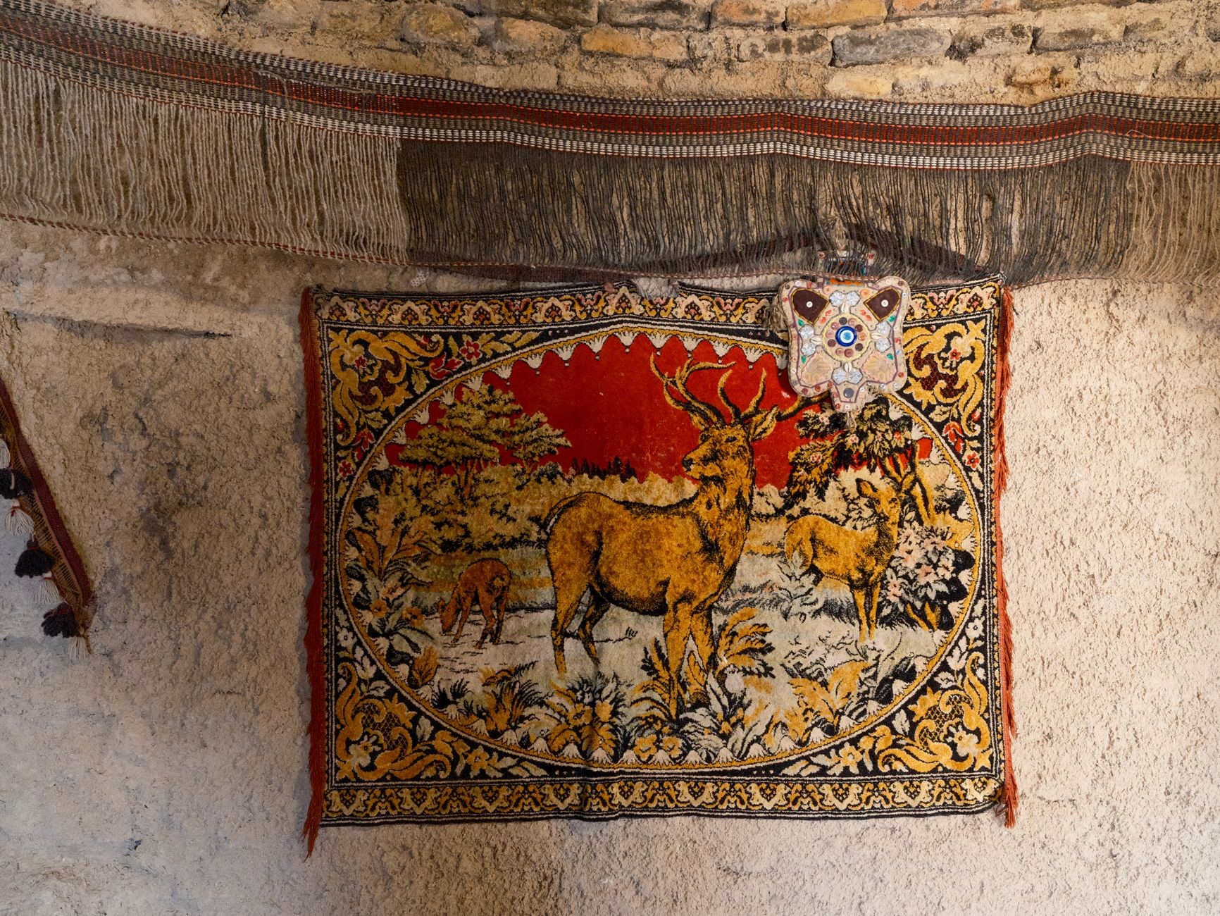 A vintage woven rug displayed vertically on a rustic interior wall