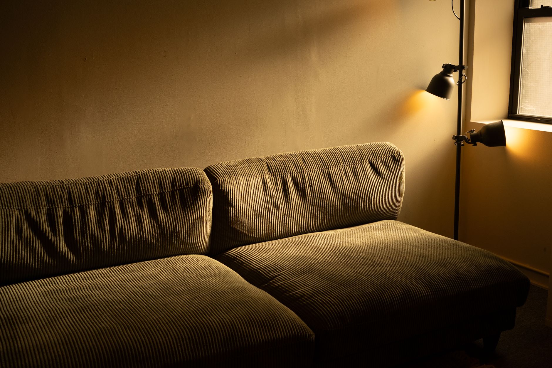Warm task and accent lighting beside a corduroy sofa