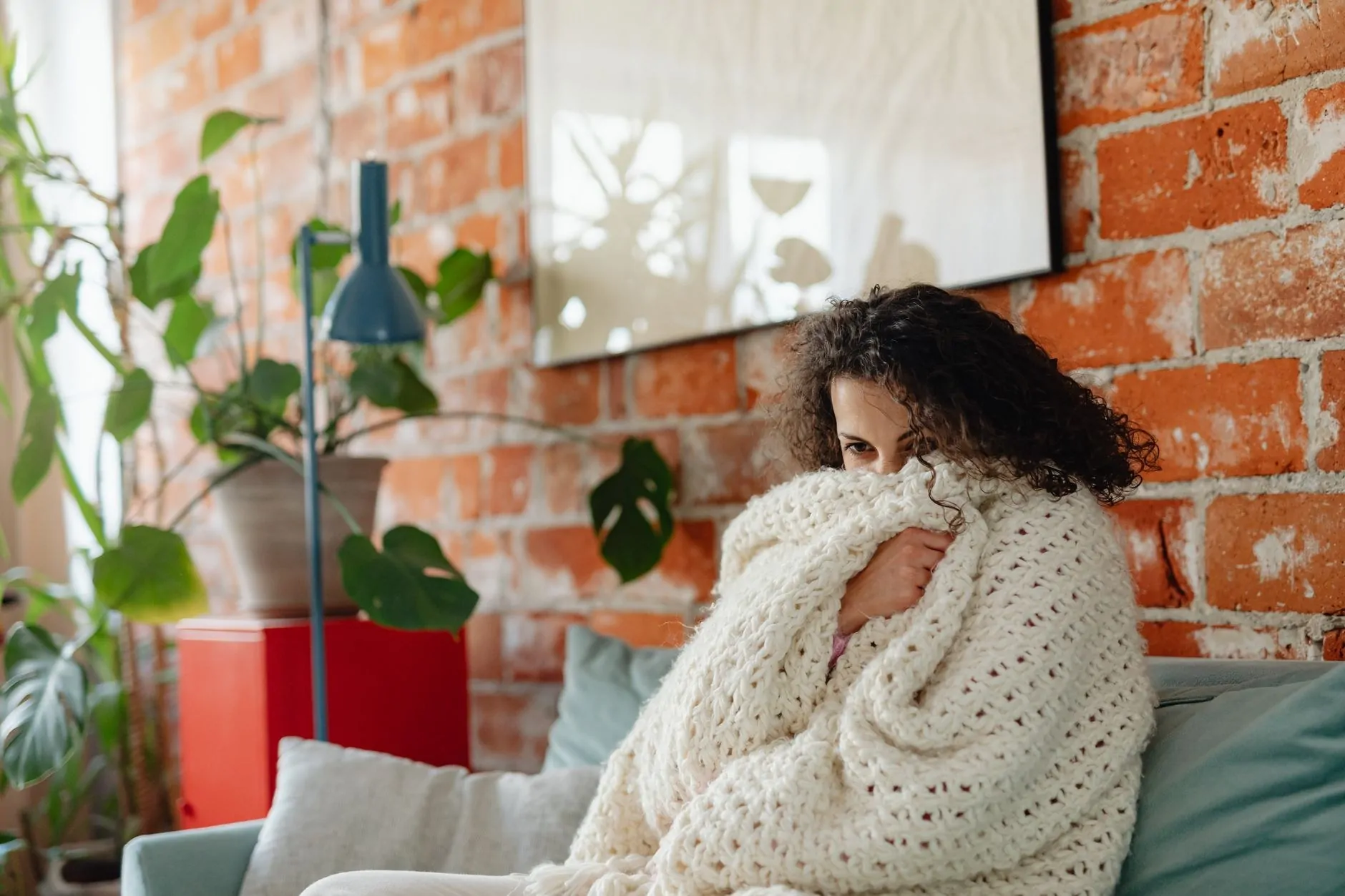 Adult wrapped in a large cozy blanket on a sofa