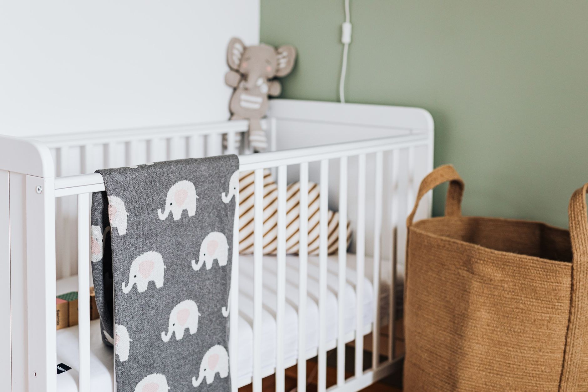 Small baby blanket hanging neatly over a crib rail