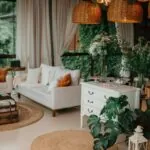 A bohemian living room with rattan pendant lights, jute rugs, white sofas, and layered greenery