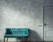 A room with a muted blue-gray wall and a teal bench, evoking the midtone blue direction of 2027 color-of-the-year picks