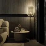 A dark, moody bedroom with a textured feature wall, warm bedding, and layered ambient lighting