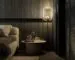 A dark, moody bedroom with a textured feature wall, warm bedding, and layered ambient lighting