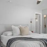 Neutral bedroom with a neatly made bed and layered white and gray blankets