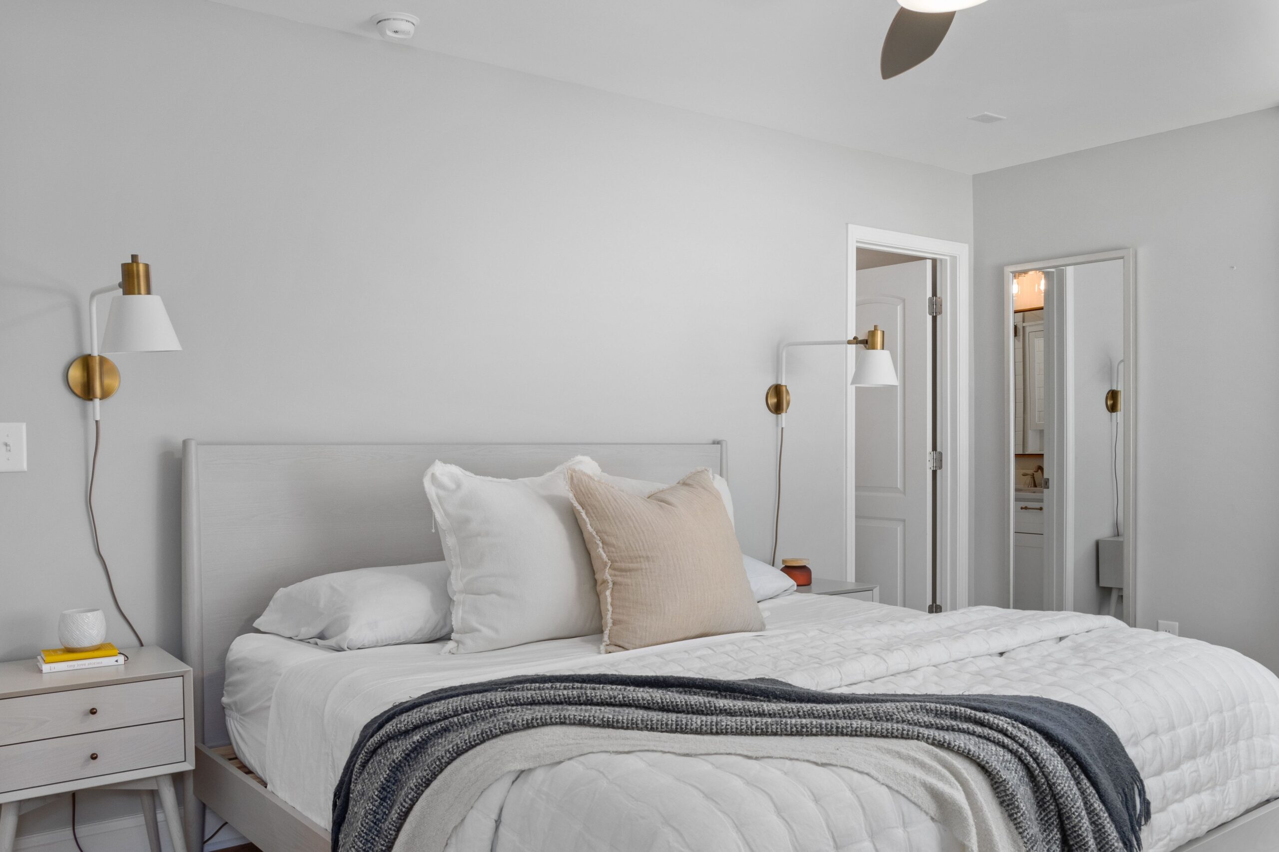 Neutral bedroom with a neatly made bed and layered white and gray blankets