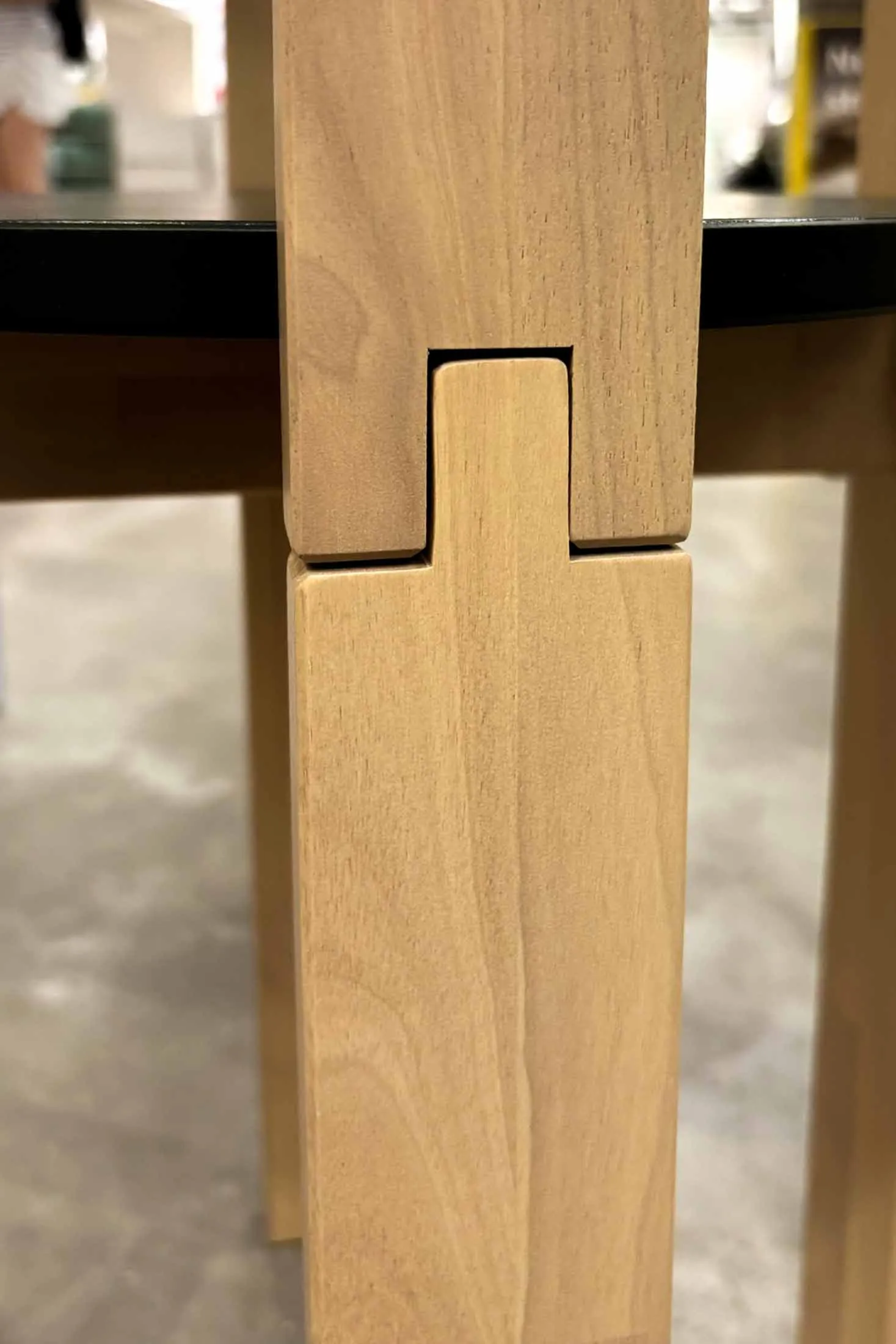 Two IKEA KOMPISHÄNG stool legs interlocked at the notch, showing how the stepped cut in one leg seats into the other