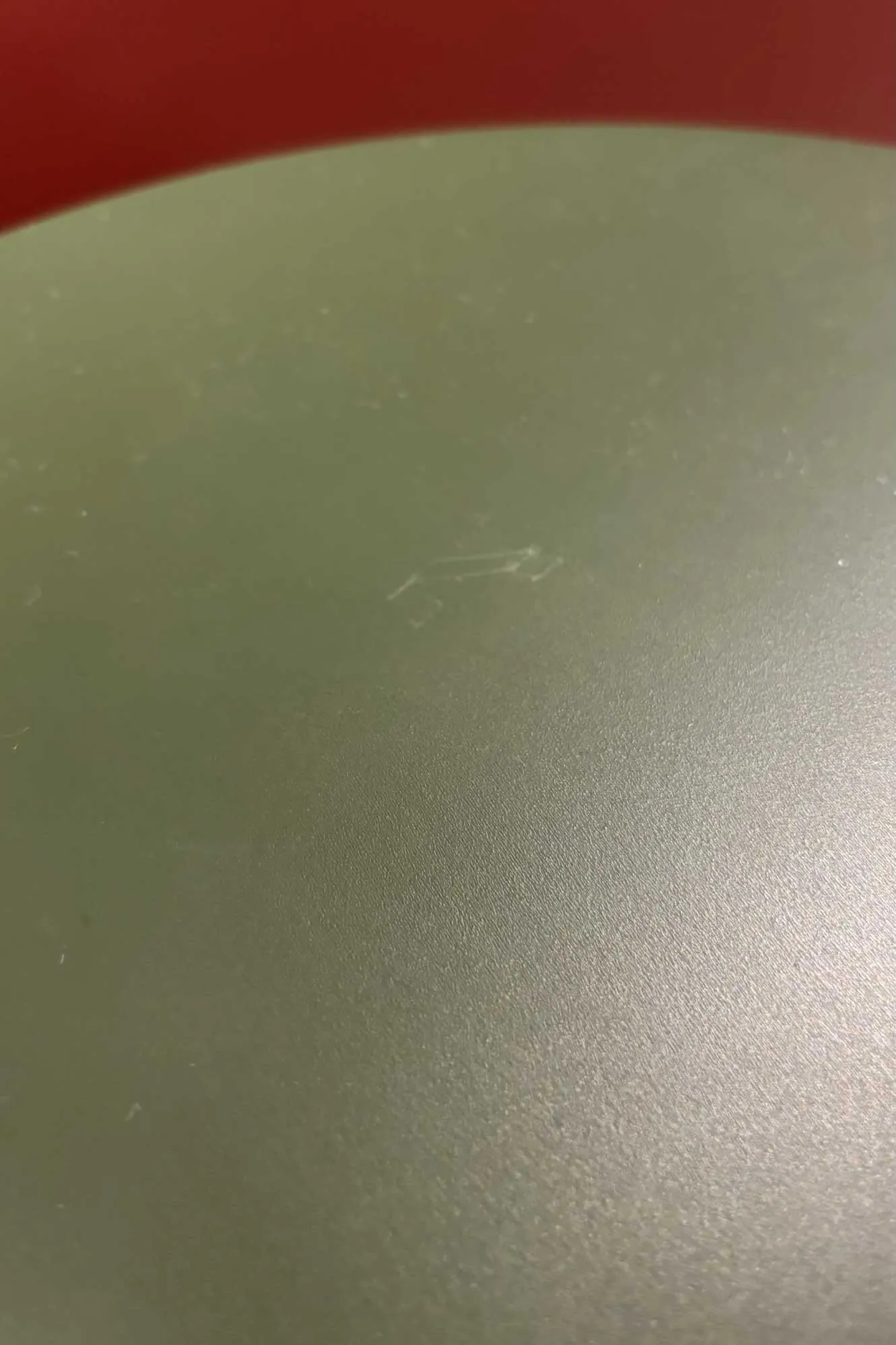 Scuff on the painted green seat of a KOMPISHÄNG floor model, showing a light mark with no wood grain visible under the paint
