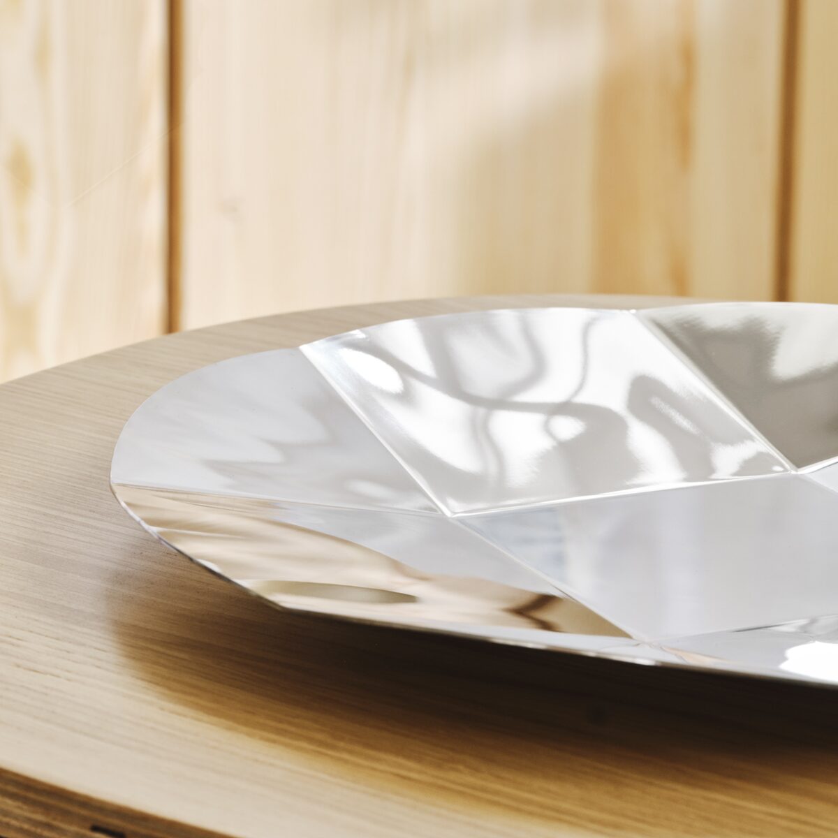 A round stainless steel platter with a faceted surface inspired by an Xbox controller D-pad