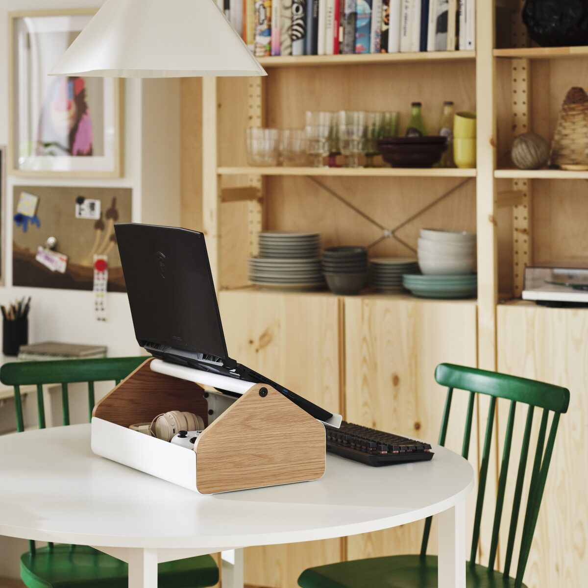 A gaming storage stand supporting a laptop with accessories stored underneath on a dining table