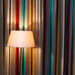 Striped curtains and a lit floor lamp illustrating color, light, and movement in an interior