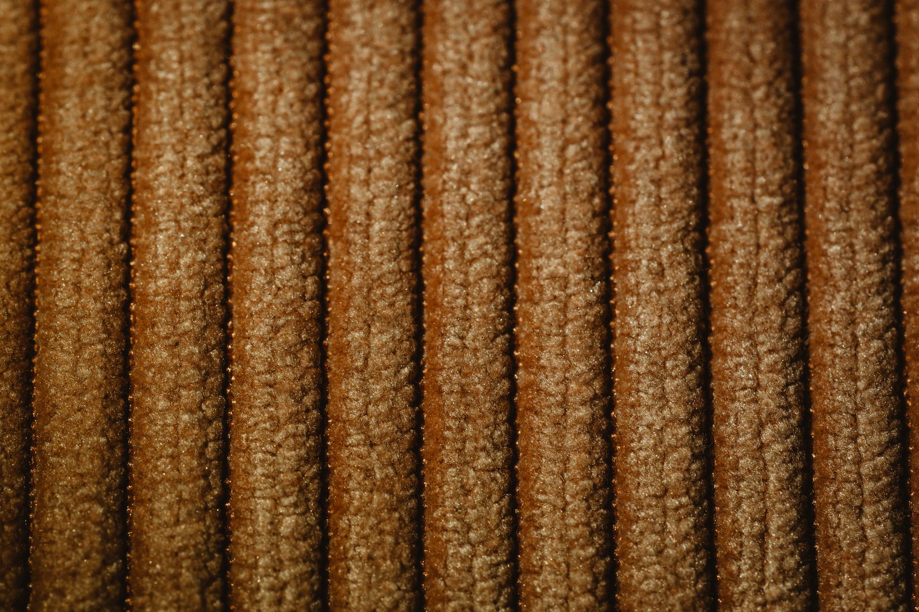 Close view of a ribbed brown textile showing texture and changing highlights