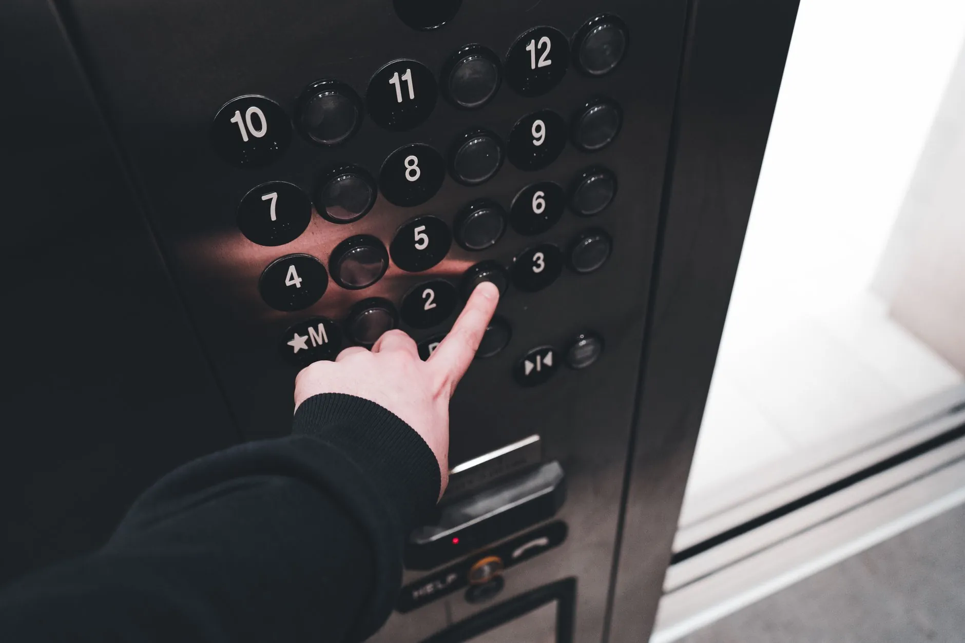 A hand using the numbered control panel inside a modern elevator