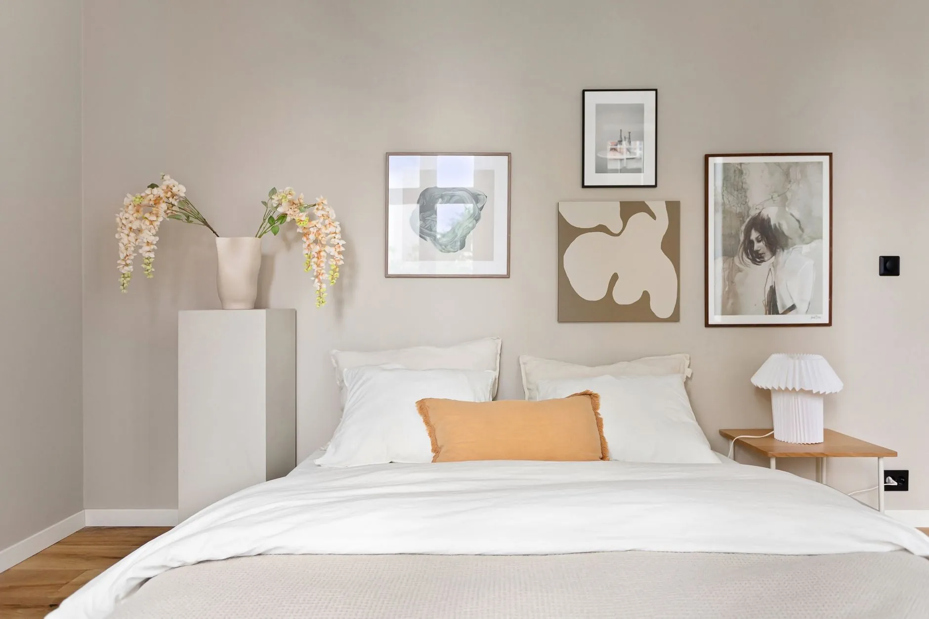 Minimalist bedroom with a balanced arrangement of framed wall art above the bed