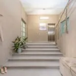 Modern neutral-toned residential interior with an elevator beside a staircase