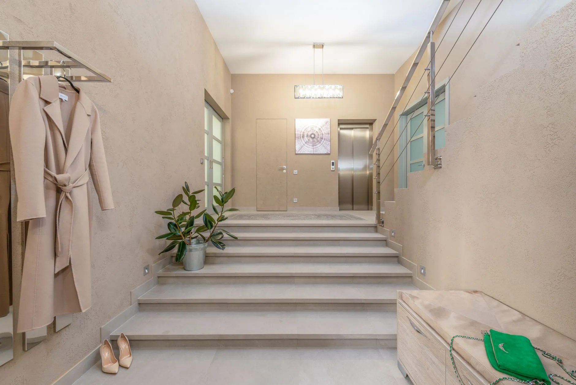 Modern neutral-toned residential interior with an elevator beside a staircase