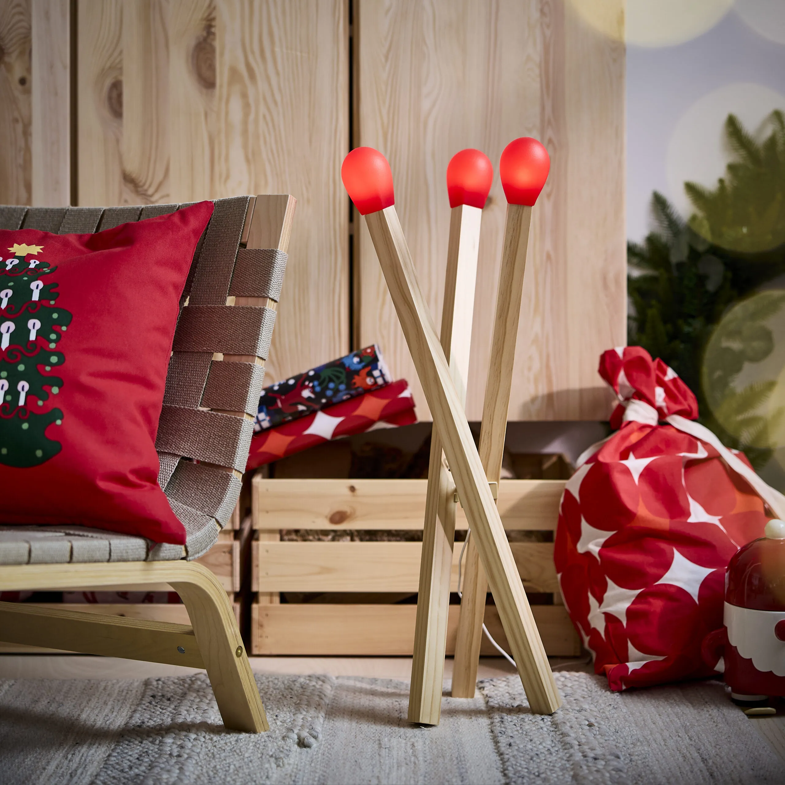 A STRALA floor lamp shaped like three oversized wooden matchsticks with glowing red tips