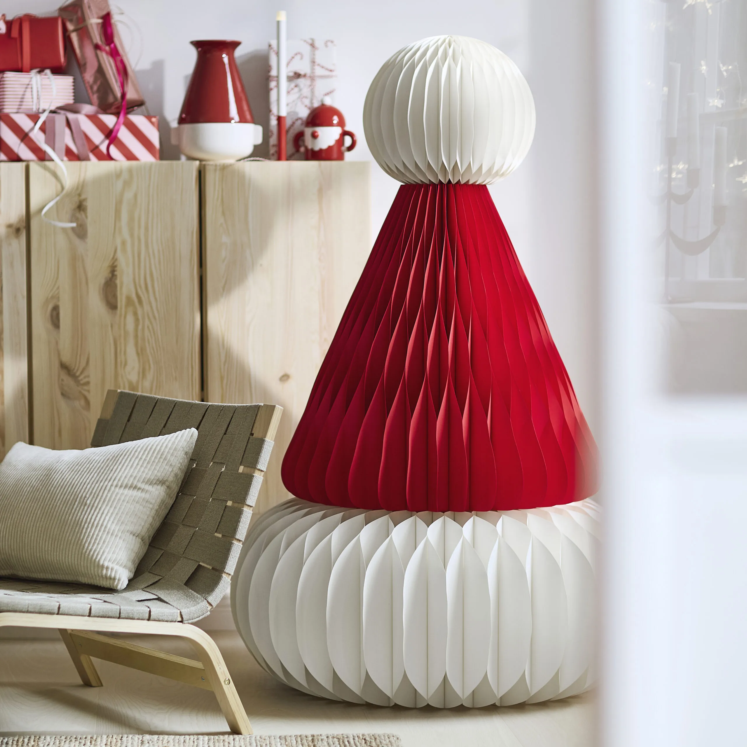 Large red and white VINTERFINT foldable paper decorations beside a lounge chair