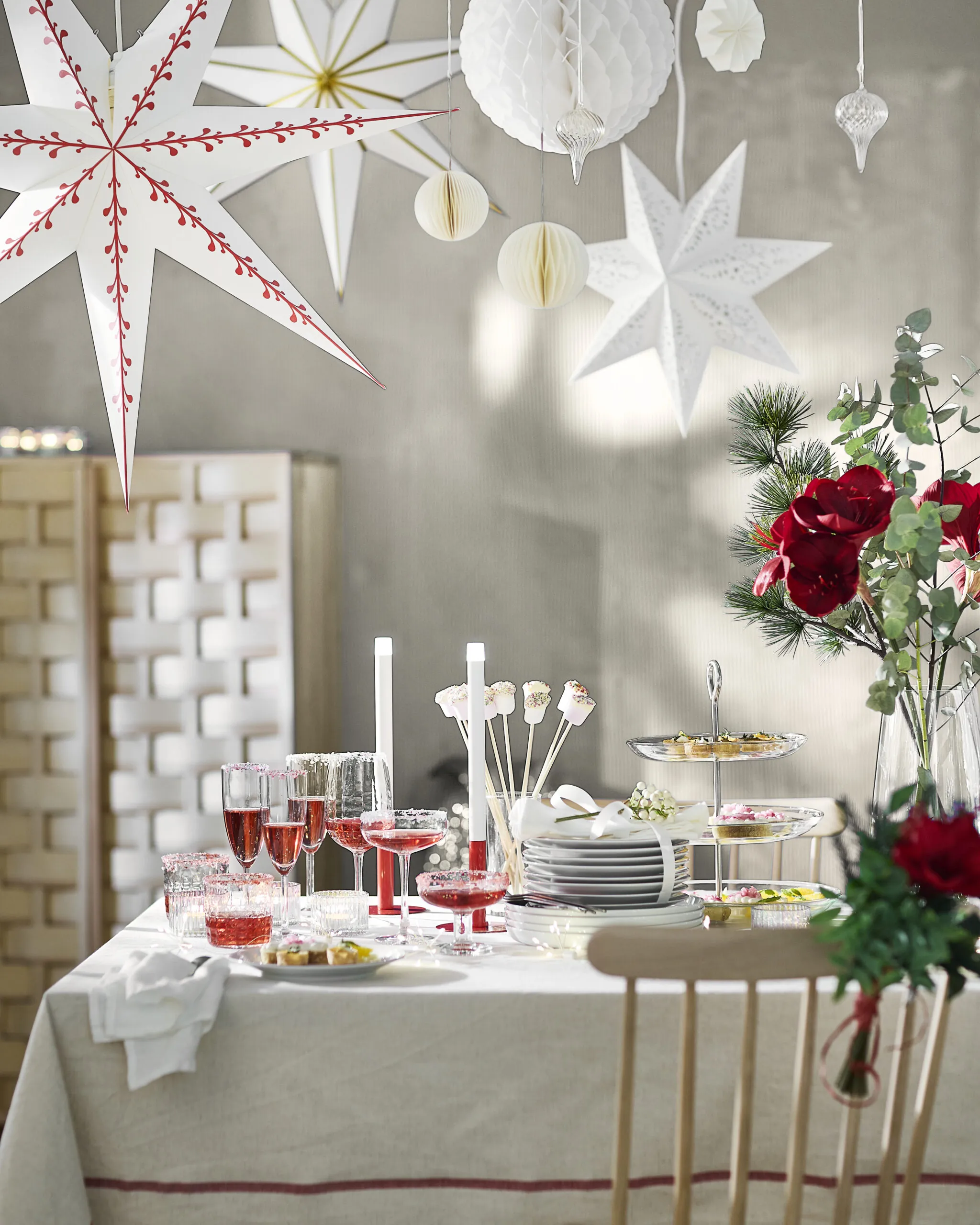 A holiday table styled with VINTERFINT pieces beneath STRALA paper stars