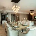 Open-plan dining and living area with pendant clusters, recessed ceiling lights and a floor lamp