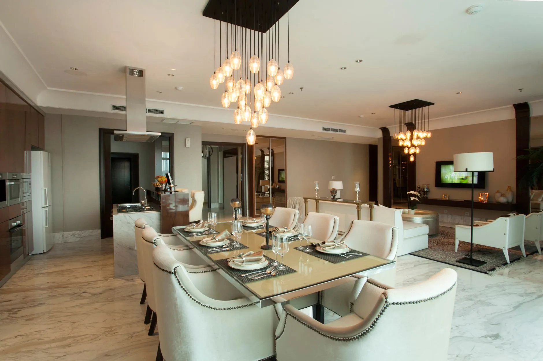 Open-plan dining and living area with pendant clusters, recessed ceiling lights and a floor lamp