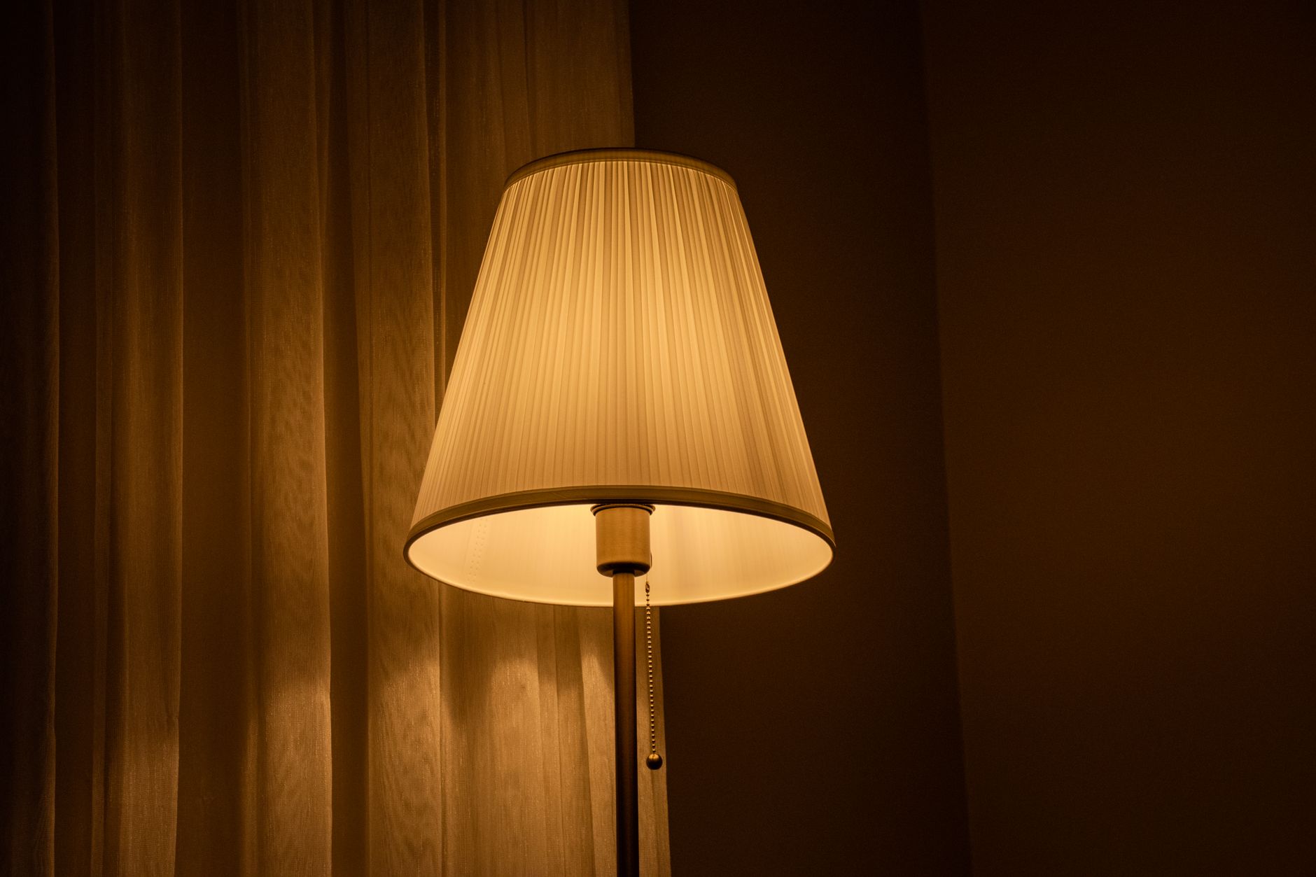 Table lamp casting warm amber light against dark curtains