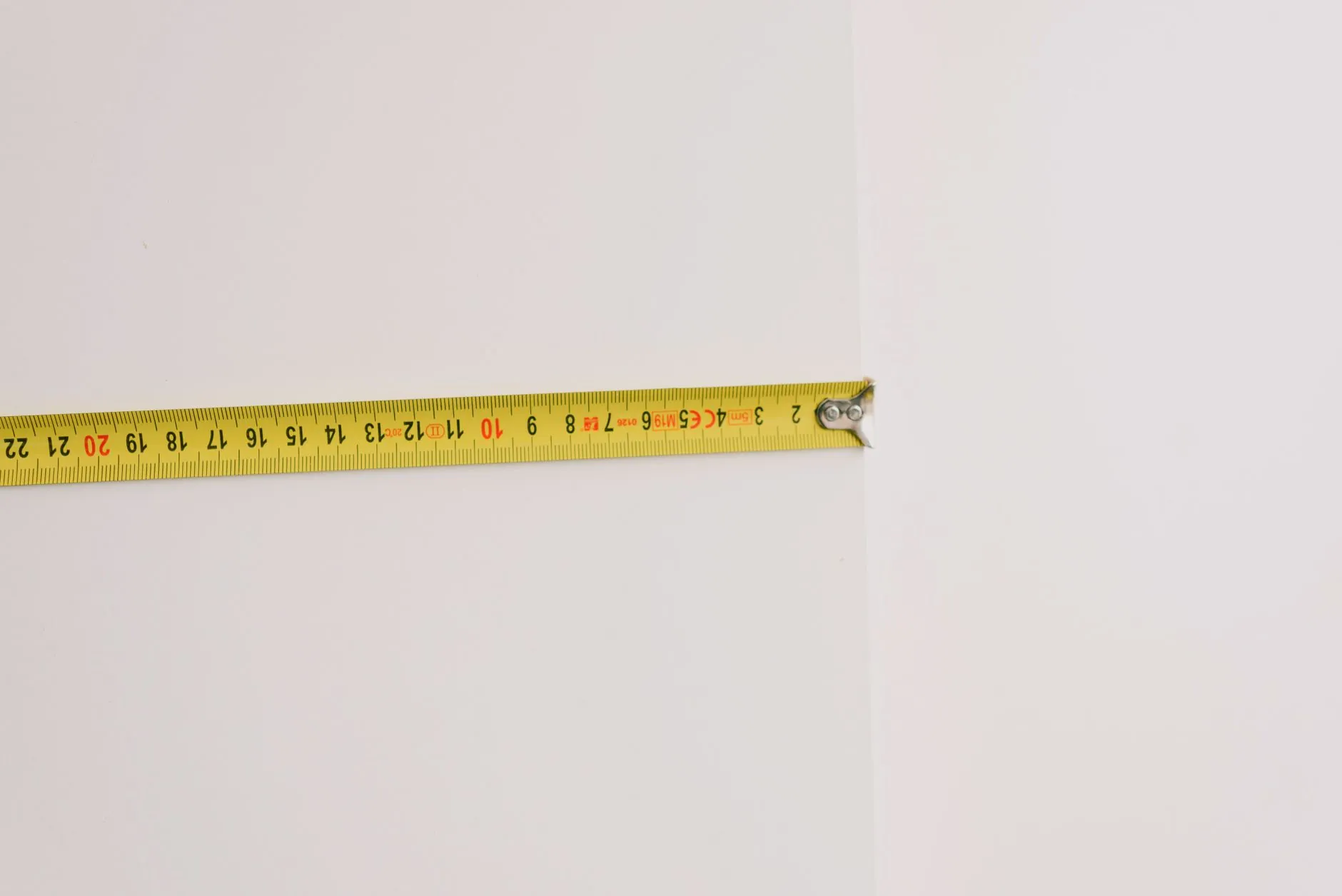Yellow measuring tape extended across a wall before planning a bedroom layout