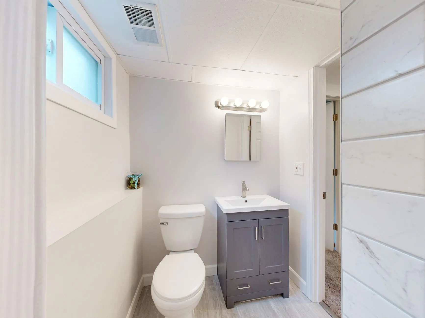 Small bright bathroom with a compact vanity, toilet, and clear floor space