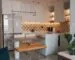 Warm modern kitchen with upholstered bench seating, wood table, plants, and layered lighting