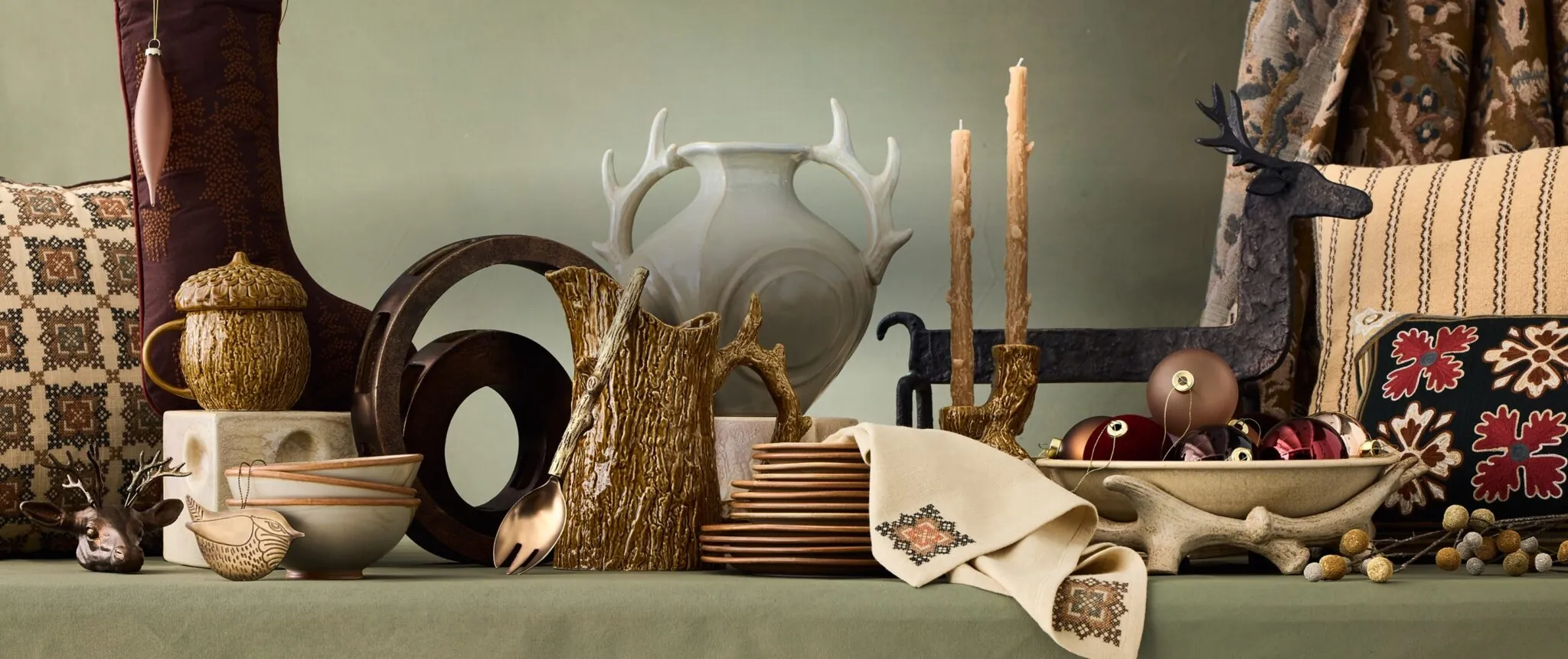 West Elm x Lone Fox holiday tablescape with faux bois vessels, an antler vase, taper candles, embroidered linens and tapestry pillows