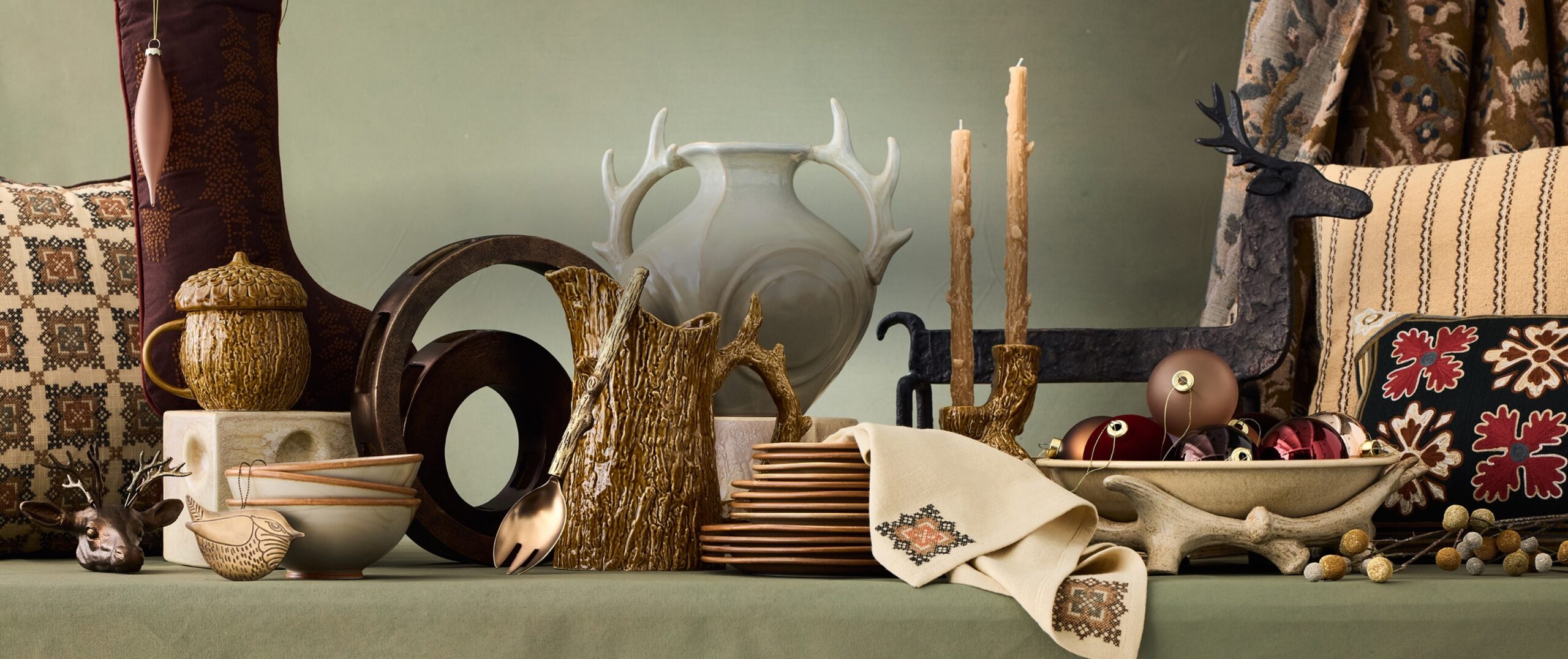 West Elm x Lone Fox holiday tablescape with faux bois vessels, an antler vase, taper candles, embroidered linens and tapestry pillows