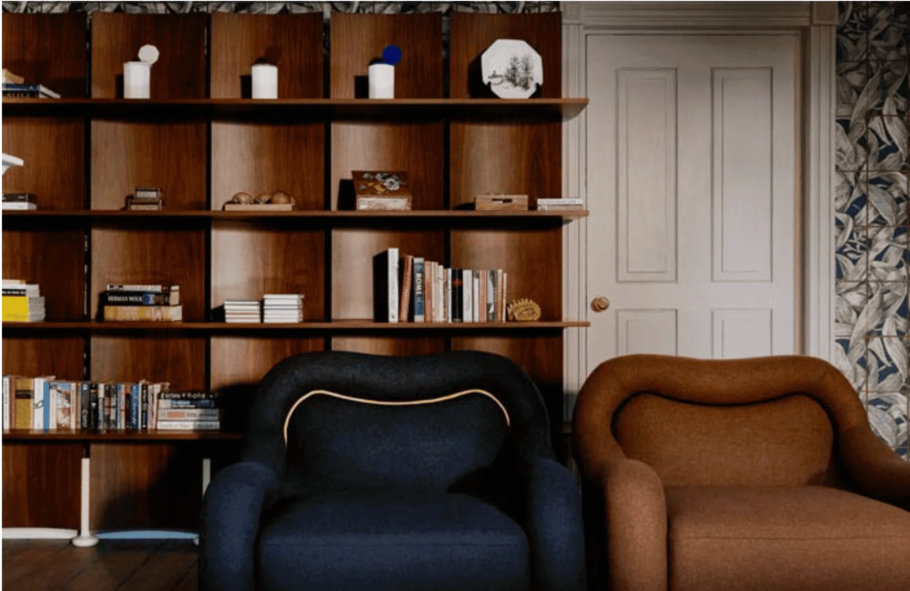 Two sculptural Baisi Guadagnino armchairs in front of library shelving