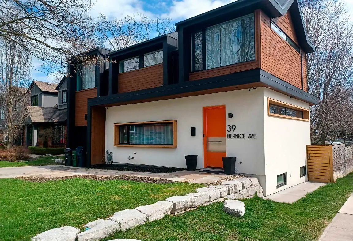 Modern home exterior with custom windows and an orange entry door