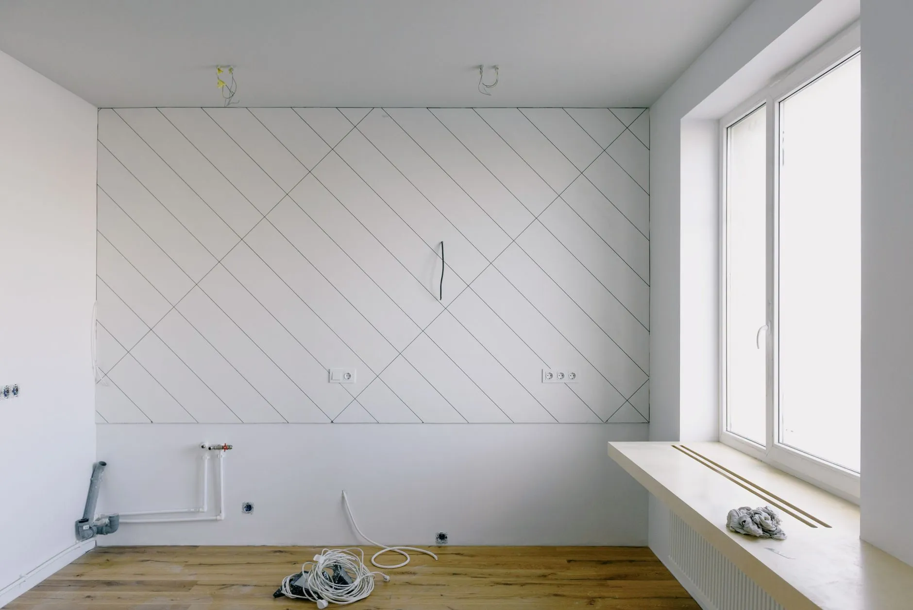 Unfinished bright room with exposed service points and coiled cable on the floor