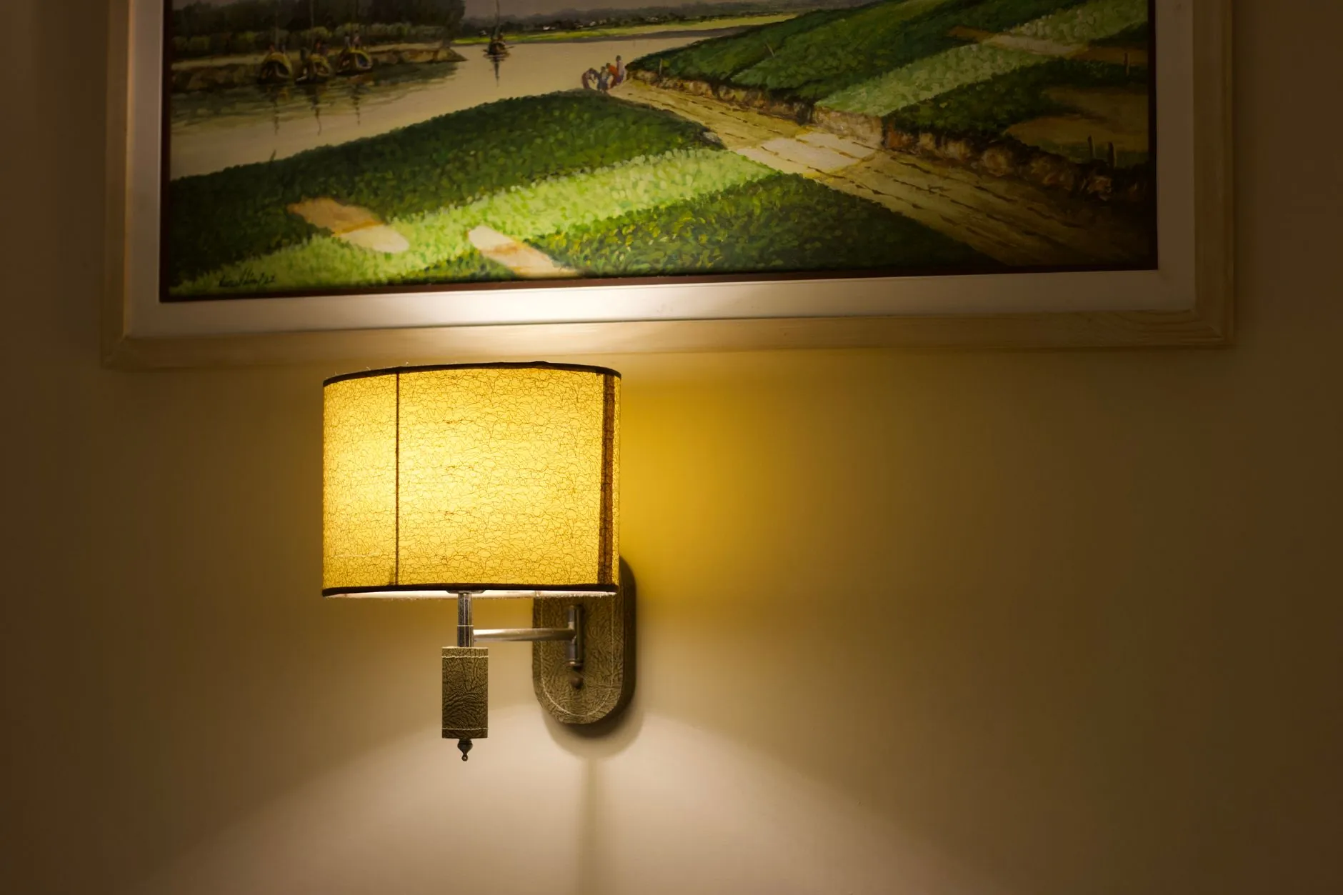 Warm wall lamp illuminating artwork and a painted wall